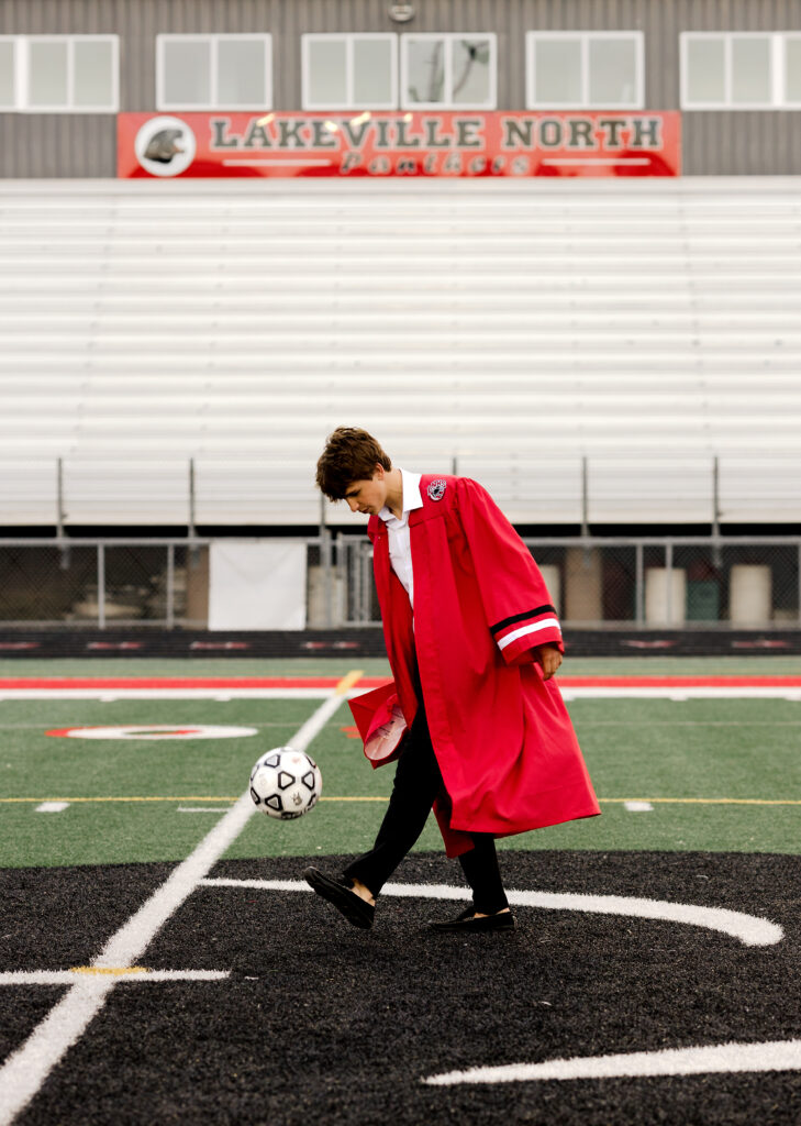 North Lakeville high school senior kicking a soccer ball during an 'In Action' photoshoot, showcasing athletic passion and skill.